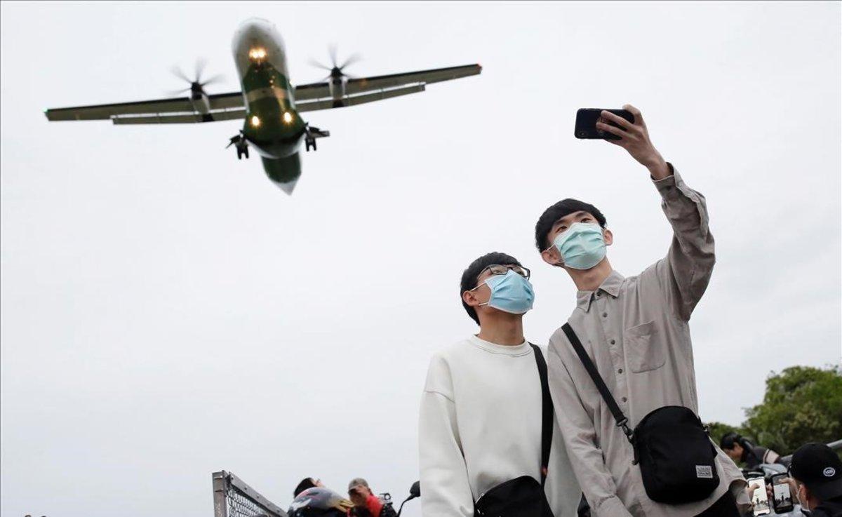 Dos jóvenes con mascarillas para protegerse frente al coronavirus se retratan en el aeropuerto de Taipei (Taiwán).