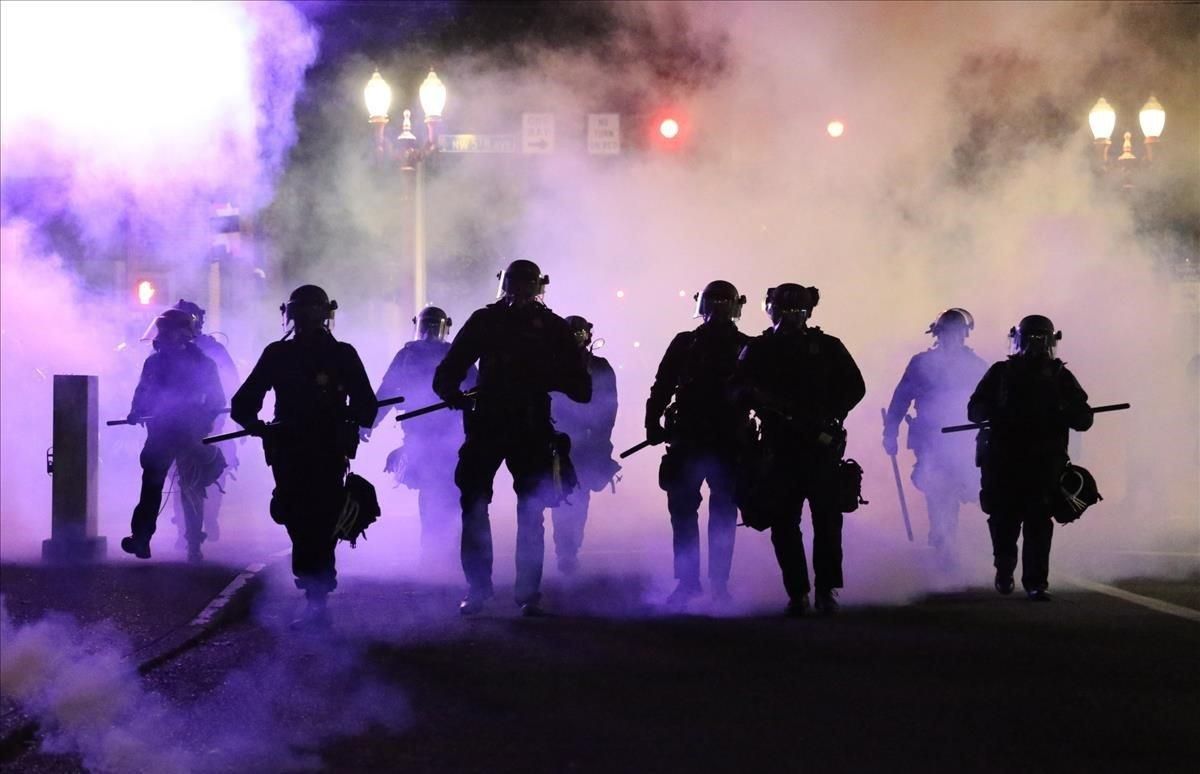 Policías caminan envueltos por gases lacrimógenos en Portland. Policías caminan envueltos por gases lacrimógenos en Portland.