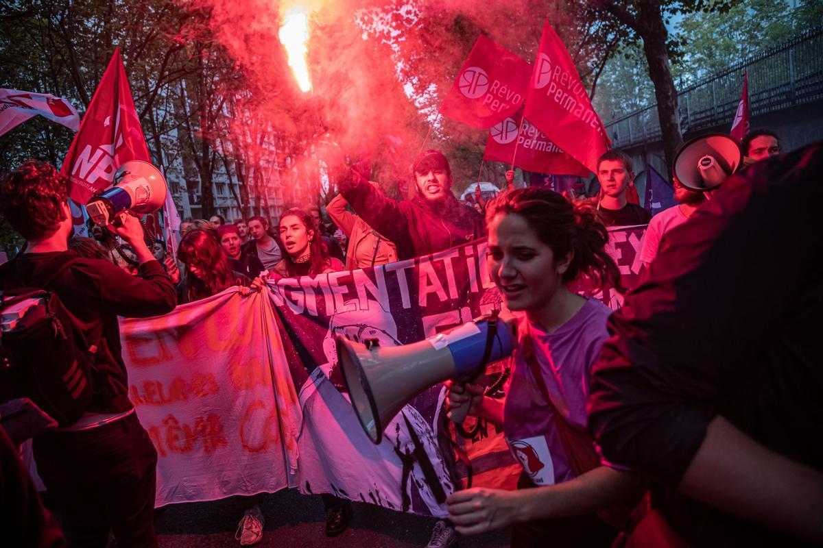 Los manifestantes encienden bengalas rojas mientras participan en una manifestación interprofesional como parte de la huelga general para mejorar los salarios en París, Francia.