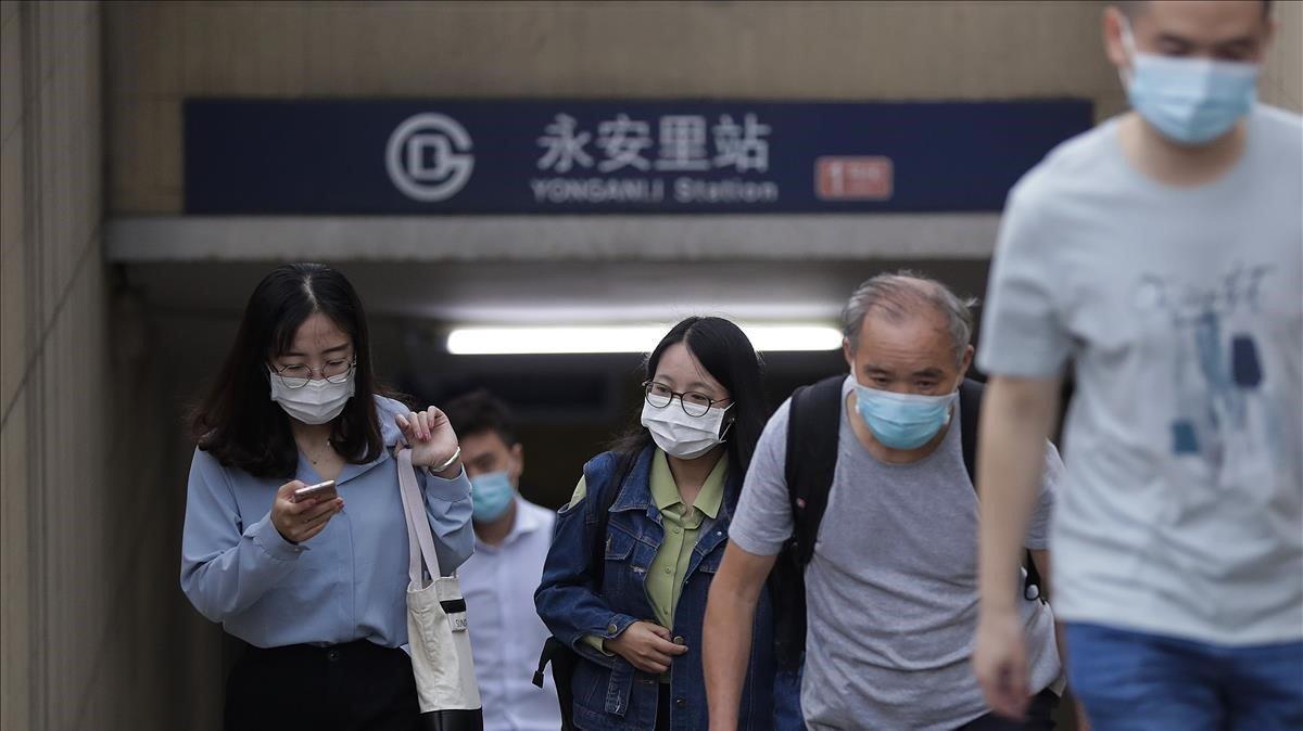 Un grupo de viajeros salen de la boca al metro de una estación de Pekín.