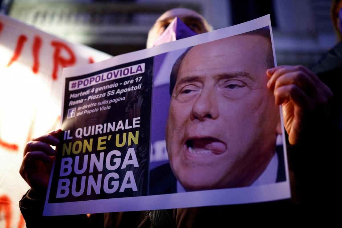 Un hombre sostiene un cartel contra Silvio Berlusconi.
