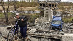 Un hombre empuja su bicicleta sobre los escombros de un puente destruido cerca de Kiev.