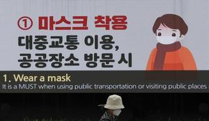 Una mujer pasa junto a una pantalla mostrando medidas de precaución par evitar la propagación del coronavirus, en Seúl, este domingo.