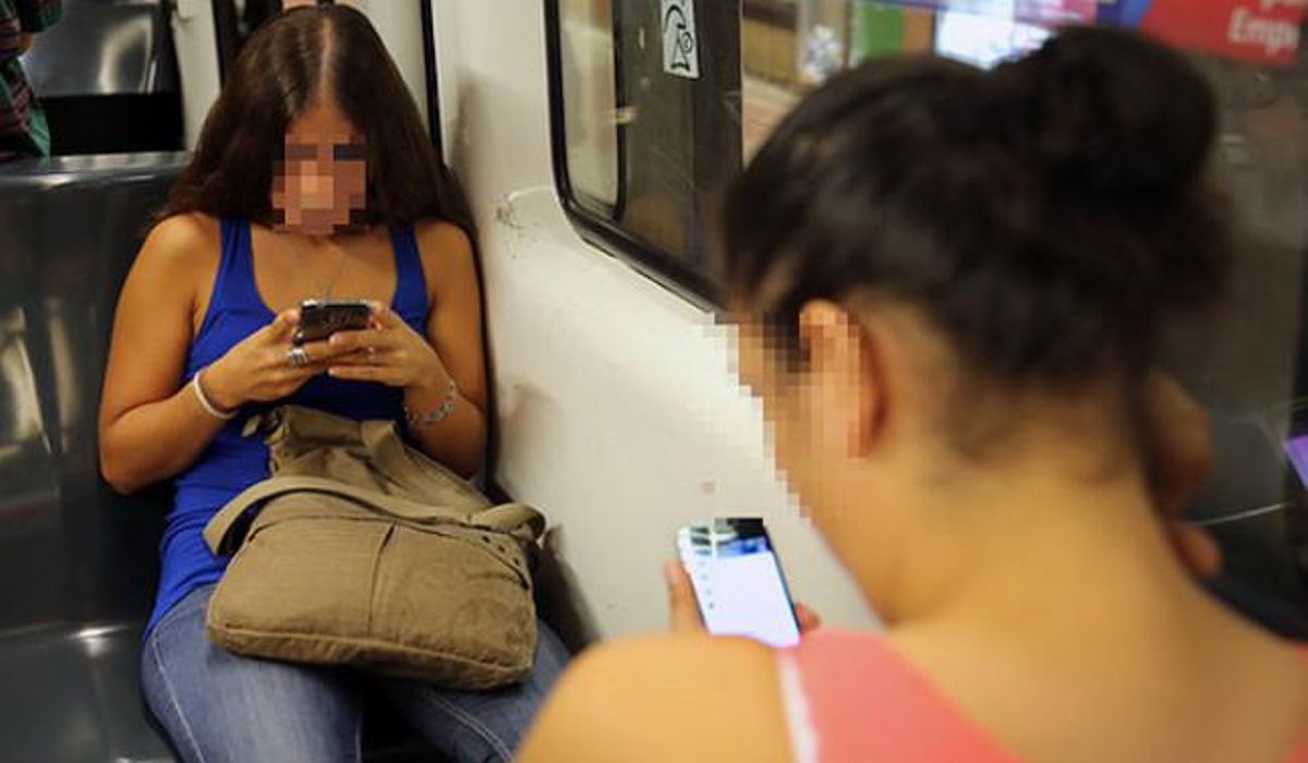 Dos chicas chatean por móvil en un vagón del metro de Barcelona. Dos chicas chatean por móvil en un vagón del metro de Barcelona.