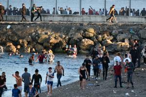 Personas migrantes caminan por la playa del Tarajal, en Ceuta, el pasado 17 de mayo de 2021. 