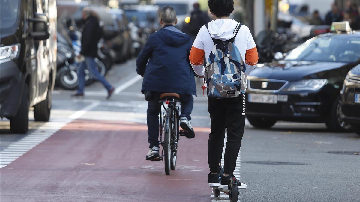 Un joven circula en patinete eléctrico por el carril bici de carrer Provença, en Barcelona.