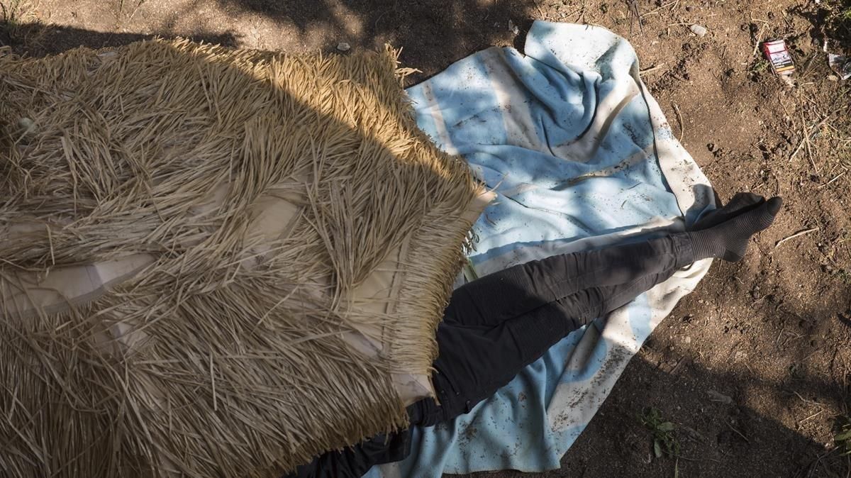 Un niño de la calle duerme bajo una sombrilla en un campamento de la montaña de Montjuïc. Un niño de la calle duerme bajo una sombrilla en un campamento de la montaña de Montjuïc.