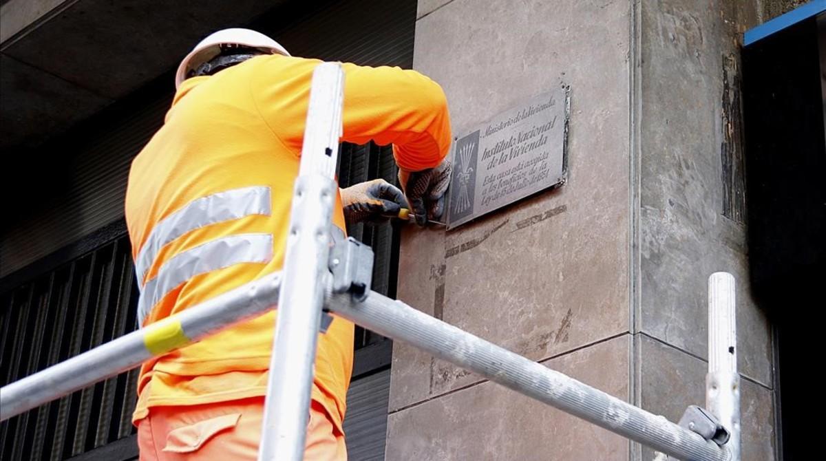 Un operario retira una placa franquista de un edificio de la calle de Còrsega, este lunes.
