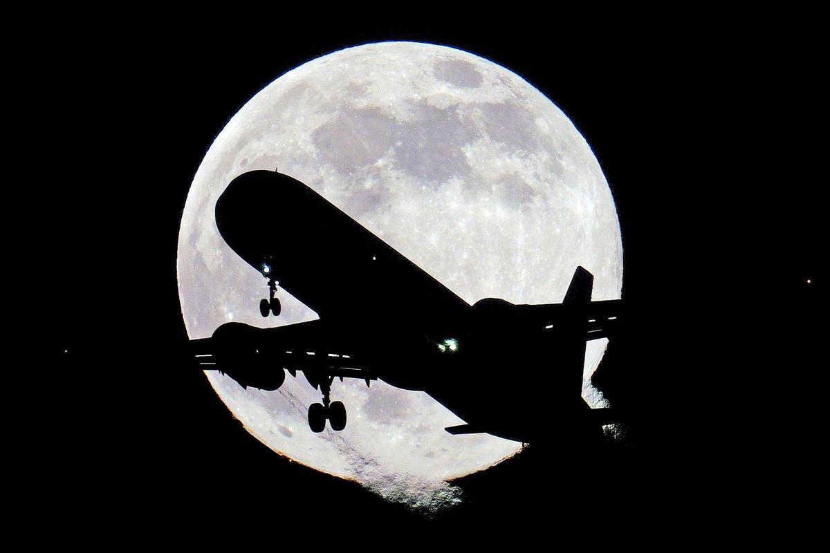 Este 17 de enero de 2022, un avión surca el cielo del Reino Unido mientras nace la primera luna llena del año.