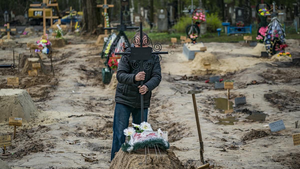 Un hombre sujeta una cruz, tras el entierro de un familiar muerto durante la guerra en Ucrania, en la ciudad de Chernihiv.