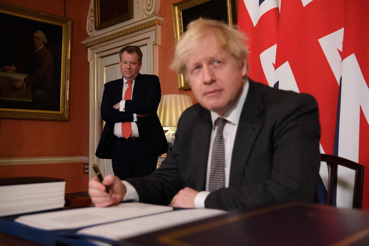 El primer ministro británico, Boris Johnson, en el momento de firmar el acuerdo con la UE el 30 de diciembre de 2020 ante la mirada de David Frost.