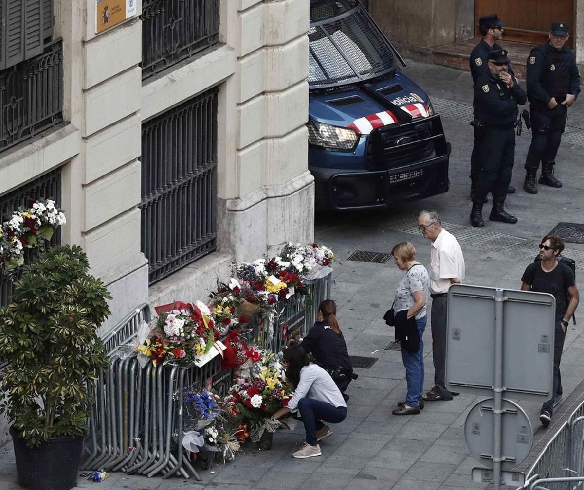 Varias personas depositan flores en la entrada de la Jefatura de la Policía Nacional en la Via Laietana.