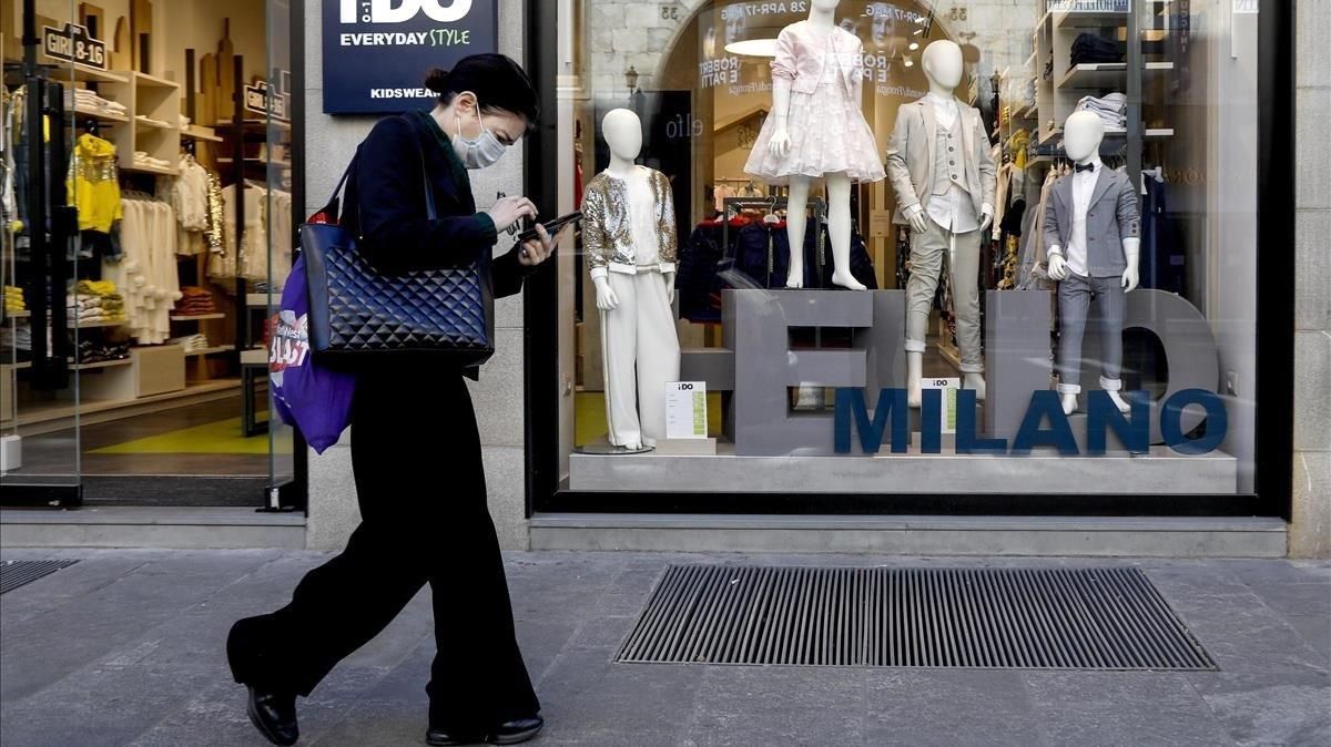 Una mujer pasa frente a una tienda de ropa para niños, este miércoles en Milán. Una mujer pasa frente a una tienda de ropa para niños, este miércoles en Milán.