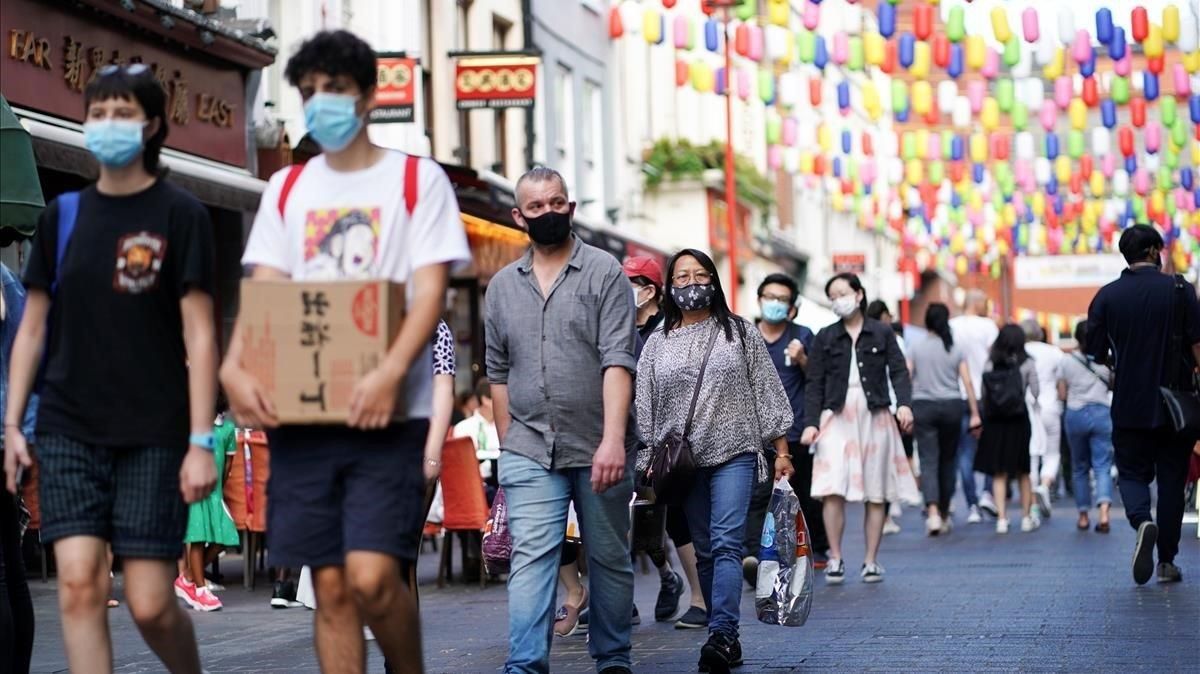Ciudadanos con mascarilla caminan por el barrio chino de Londres, este domingo. Ciudadanos con mascarilla caminan por el barrio chino de Londres, este domingo.
