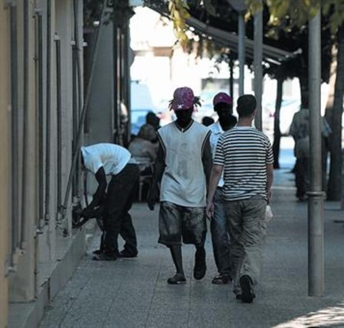 Unos inmigrantes caminan por una céntrica calle de Salt. Unos inmigrantes caminan por una céntrica calle de Salt.