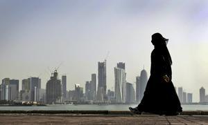 Una mujer qatarí con el skyline de Doha de fondo.