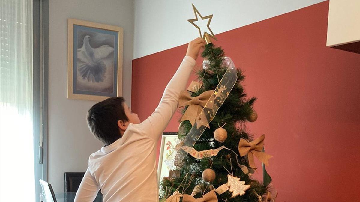 El hijo de la farmacéutica Gemma del Caño coloca una estrella en el árbol de Navidad familiar.