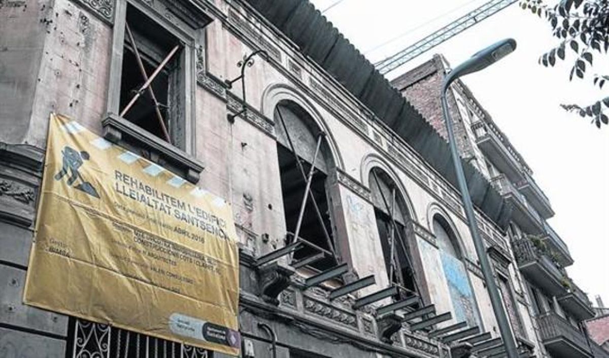 Fachada principal del edificio de La Lleialtat Santsenca, con las ventanas apuntaladas y con un cartel con los datos de las empresas que no acabaron la rehabilitación. Fachada principal del edificio de La Lleialtat Santsenca, con las ventanas apuntaladas y con un cartel con los datos de las empresas que no acabaron la rehabilitación.