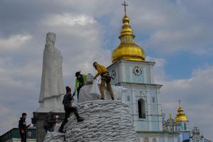 Voluntarios protegen con sacos de arena un monumento en Kiev.