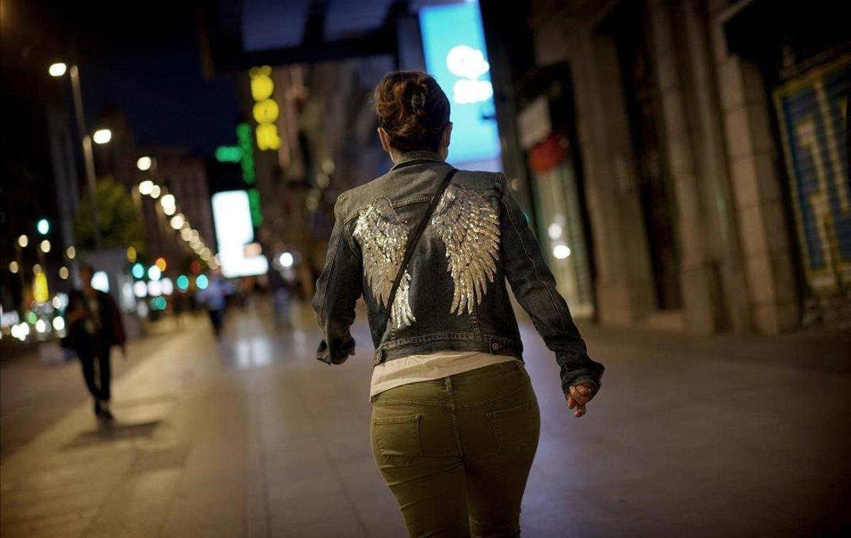  Una mujer anda por el centro de Madrid, de noche.