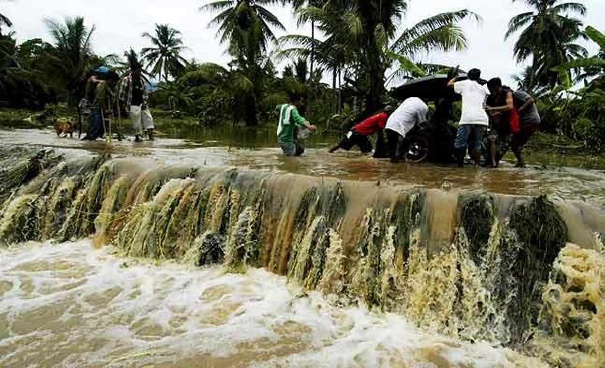 Equipos de rescate empujan un triciclo motorizado estancado en un camino inundado por las lluvias al sur de Filipinas. Equipos de rescate empujan un triciclo motorizado estancado en un camino inundado por las lluvias al sur de Filipinas.