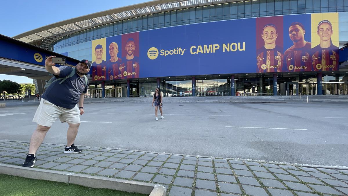 Unos aficionados posan ante el logotipo de Spotify Camp Nou.