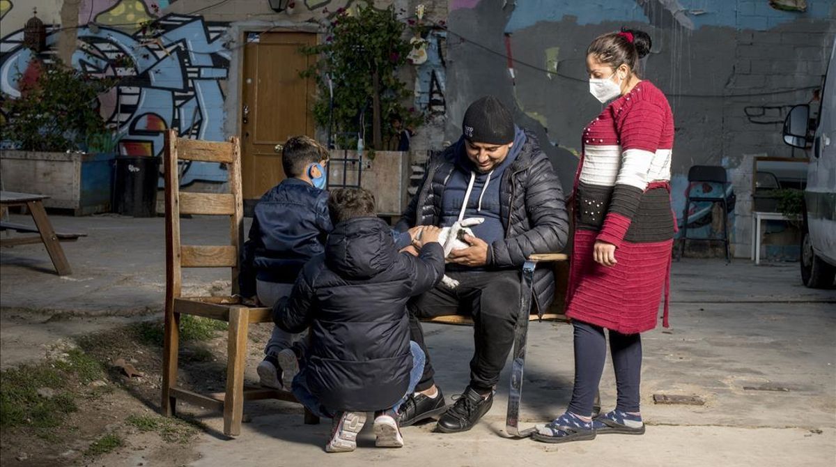 Barcelona 09 12 2020 Barcelona Valentin y su mujer Ceracela junto a su dos hijos pendientes en la foto de su mascota fotografiados en el interior de La Escocesa una de las naves en el Poblenou donde conviven okupando alrededor de cincuenta familias pendientes de su realojamiento por parte del Ajuntament Fotografia de Jordi Cotrina Barcelona 09 12 2020 Barcelona Valentin y su mujer Ceracela junto a su dos hijos pendientes en la foto de su mascota fotografiados en el interior de La Escocesa una de las naves en el Poblenou donde conviven okupando alrededor de cincuenta familias pendientes de su realojamiento por parte del Ajuntament Fotografia de Jordi Cotrina