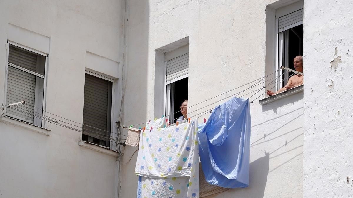 Dos personas mayores toman el sol en la ventana vivienda en Madrid. Dos personas mayores toman el sol en la ventana vivienda en Madrid.