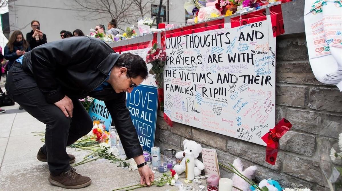 Un hombre coloca una flor en el memorial improvisado a las víctimas del atropello en Toronto.