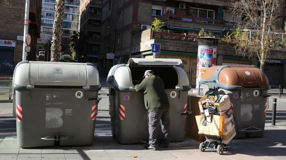 Un hombre recoge basura en unos contenedores de Barcelona, el año pasado.