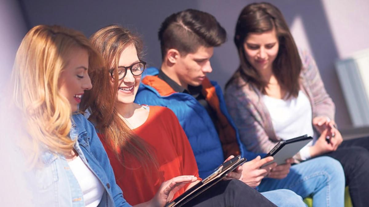 Estudiantes universitarios repasan sus apuntes en tabletas móviles. Estudiantes universitarios repasan sus apuntes en tabletas móviles.