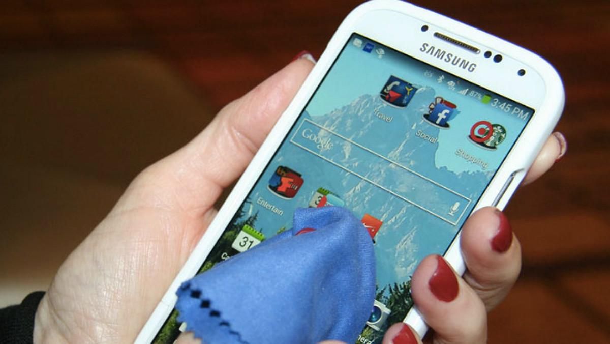 Una mujer limpia la pantalla de su teléfono móvil. Una mujer limpia la pantalla de su teléfono móvil.