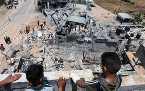 Unos civiles palestinos inspeccionan los restos de sus casas después de un ataque israelí.