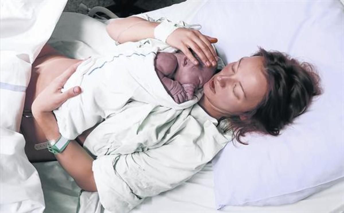 Una mujer acaricia a su hijo recién nacido en la cama de un hospital. Una mujer acaricia a su hijo recién nacido en la cama de un hospital.