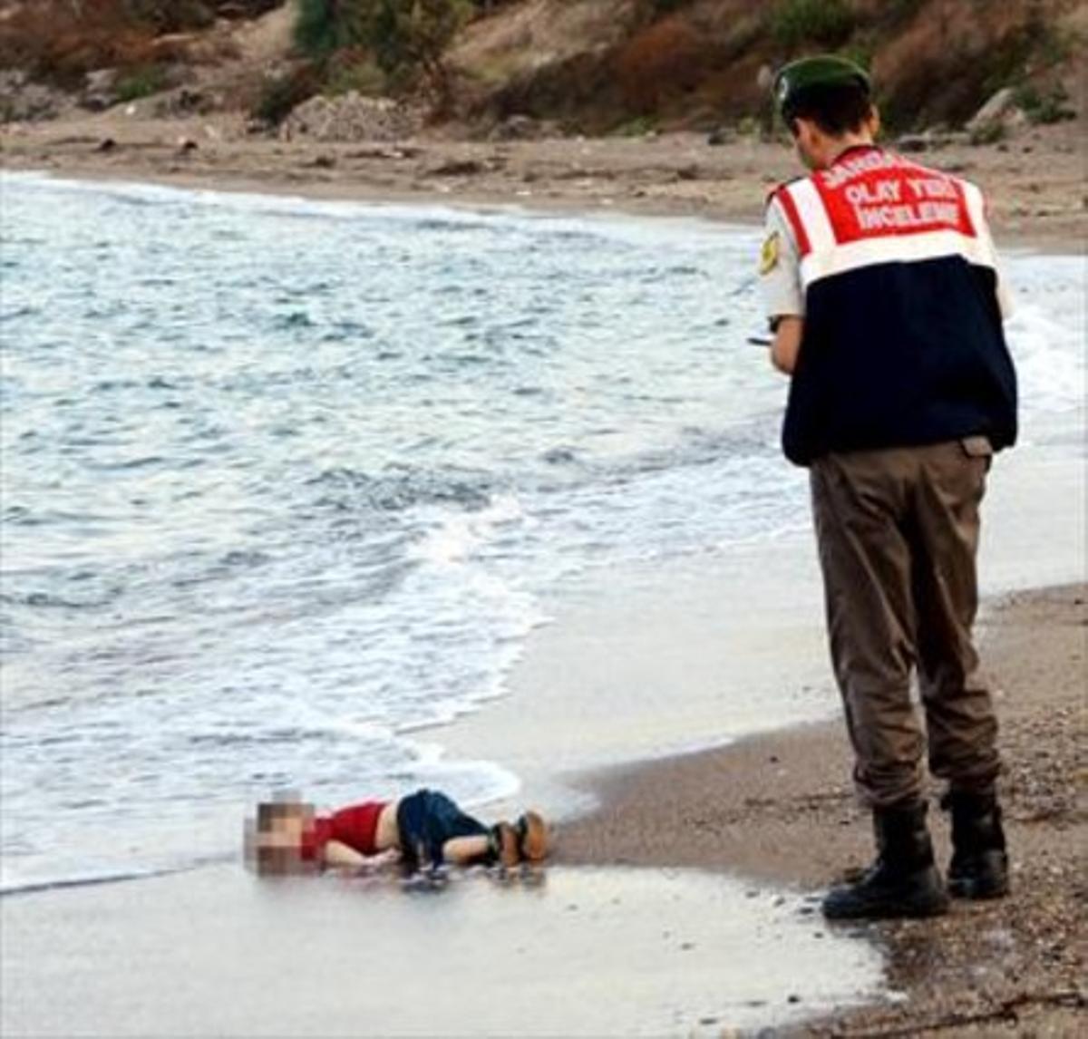 El niño sirio Aylan Kurdi, ante un guardacostas en la playa de Turquía a la que llegó su cadáver.