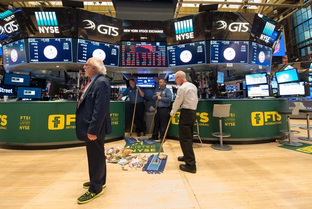 TOPSHOT - Personal sweep the floor after the closing bell of the Dow Industrial Average at the New York Stock Exchange on February 5, 2018 in New York.