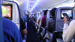 Un pasajero consulta su teléfono en la cabina de un avión.