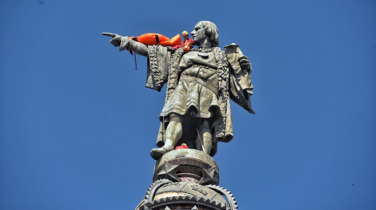 Un activista de Open Arms, encaramado a la estatua de Colón.
