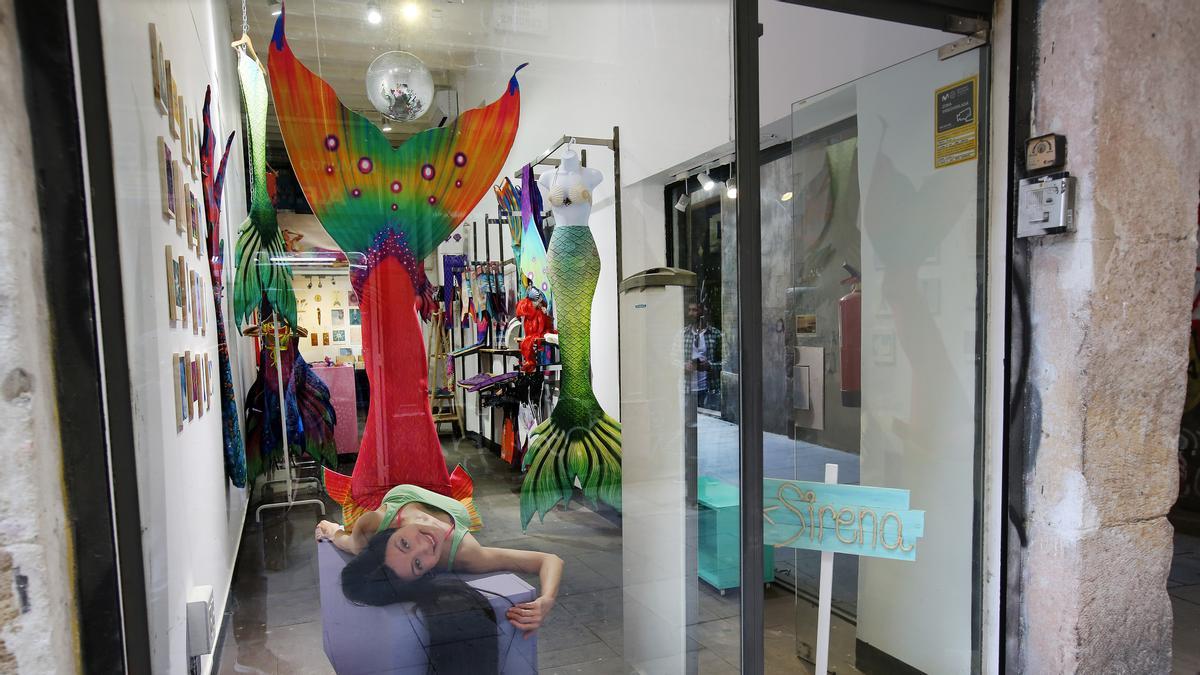 Andreina Mermaid posa con una cola de sirena de diseño propio en el escaparate de su nueva tienda, Mermaiding House, en Ciutat Vella. 