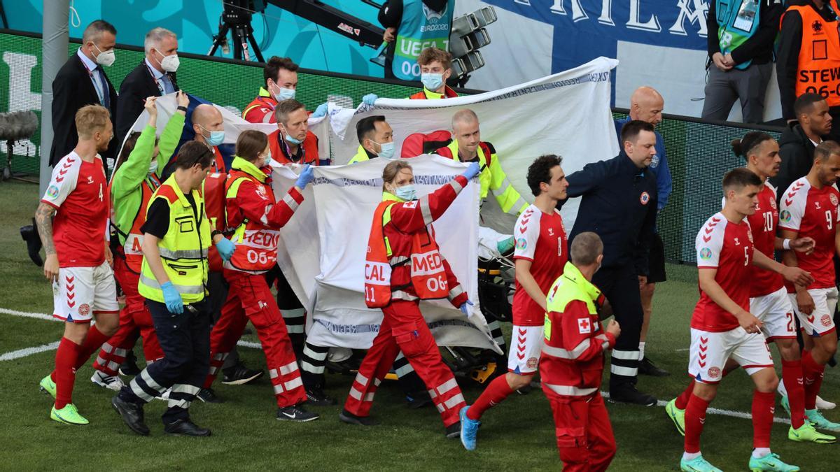 Players escort paramedics as Denmark’s midfielder Christian Eriksen is evacuated from the pitch during the UEFA EURO 2020 Group B football match between Denmark and Finland at the Parken Stadium in Copenhagen on June 12, 2021. (Photo by WOLFGANG RATTAY / POOL / AFP)