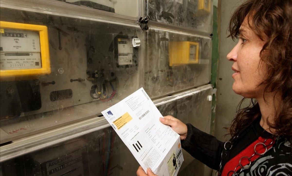Una mujer consulta una factura de la luz junto a un contador. Una mujer consulta una factura de la luz junto a un contador.