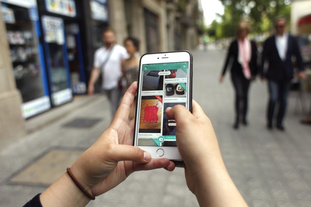 Una usuaria de Wallapop consulta la aplicación en su teléfono desde una calle de Barcelona.