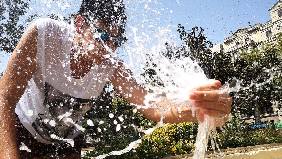 Un joven se refresca en la plaza de la Pau en Lleida Un joven se refresca en la plaza de la Pau en Lleida