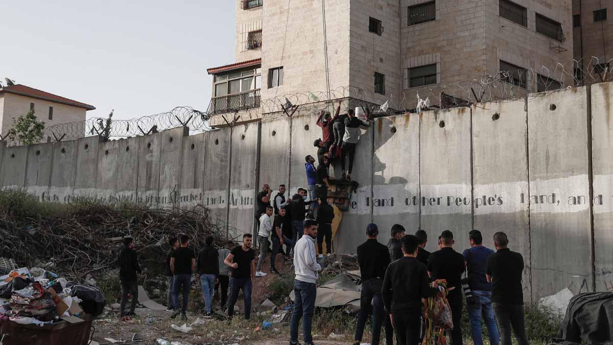Palestinos intentando saltar el muro que separa el pueblo de A-Ram de Jerusalén para acceder a la Explanada de las Mezquitas en el último viernes de Ramadán.