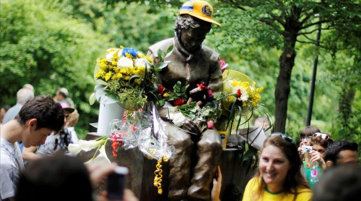Una aficionada brasileña posa junto a la estatua que recuerda a Ayrton Senna en Imola.