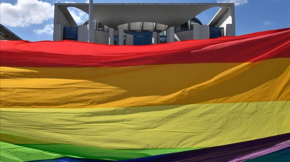 Unos activistas sostienen una bandera arcoiris frente al parlamento en Berlín. Unos activistas sostienen una bandera arcoiris frente al parlamento en Berlín.