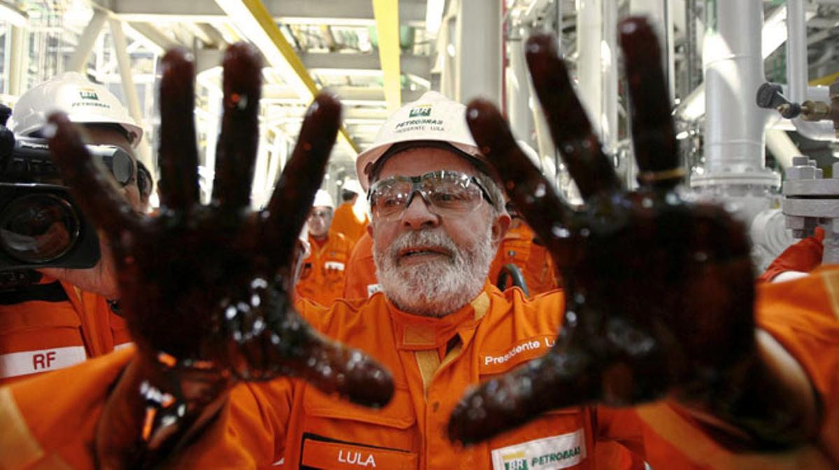 Lula con las manos impregnadas de petróleo durante el lanzamiento de una plataforma de Petrobras.