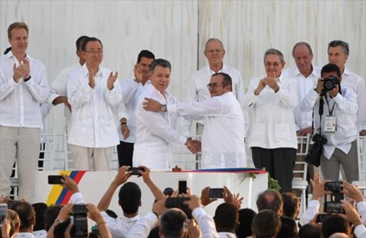Santos y Timochenko se dan la mano entre los aplausos de Ki-mon,Castro y el rey emérito Juan Carlos, entre otras personalidades. Santos y Timochenko se dan la mano entre los aplausos de Ki-mon,Castro y el rey emérito Juan Carlos, entre otras personalidades.