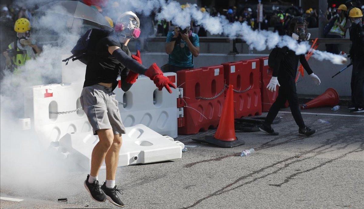 Un manifestante lanza un bote de gas lacrimógeno durante las protestas con motivo de la huelga general en Hong Kong. 
