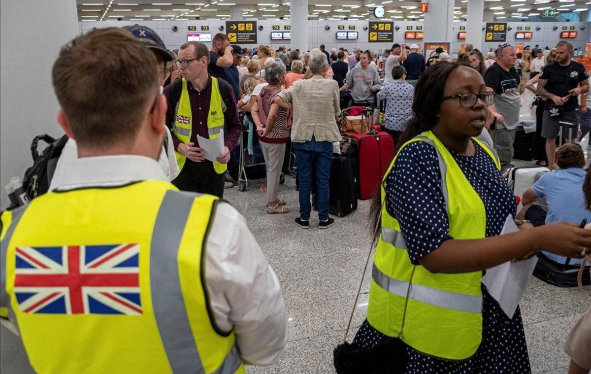 Empleados del Gobierno británico atienden, en el aeropuerto de Palma de Mallorca, a pasajeros afectados por la quiebra de Thomas Cook.